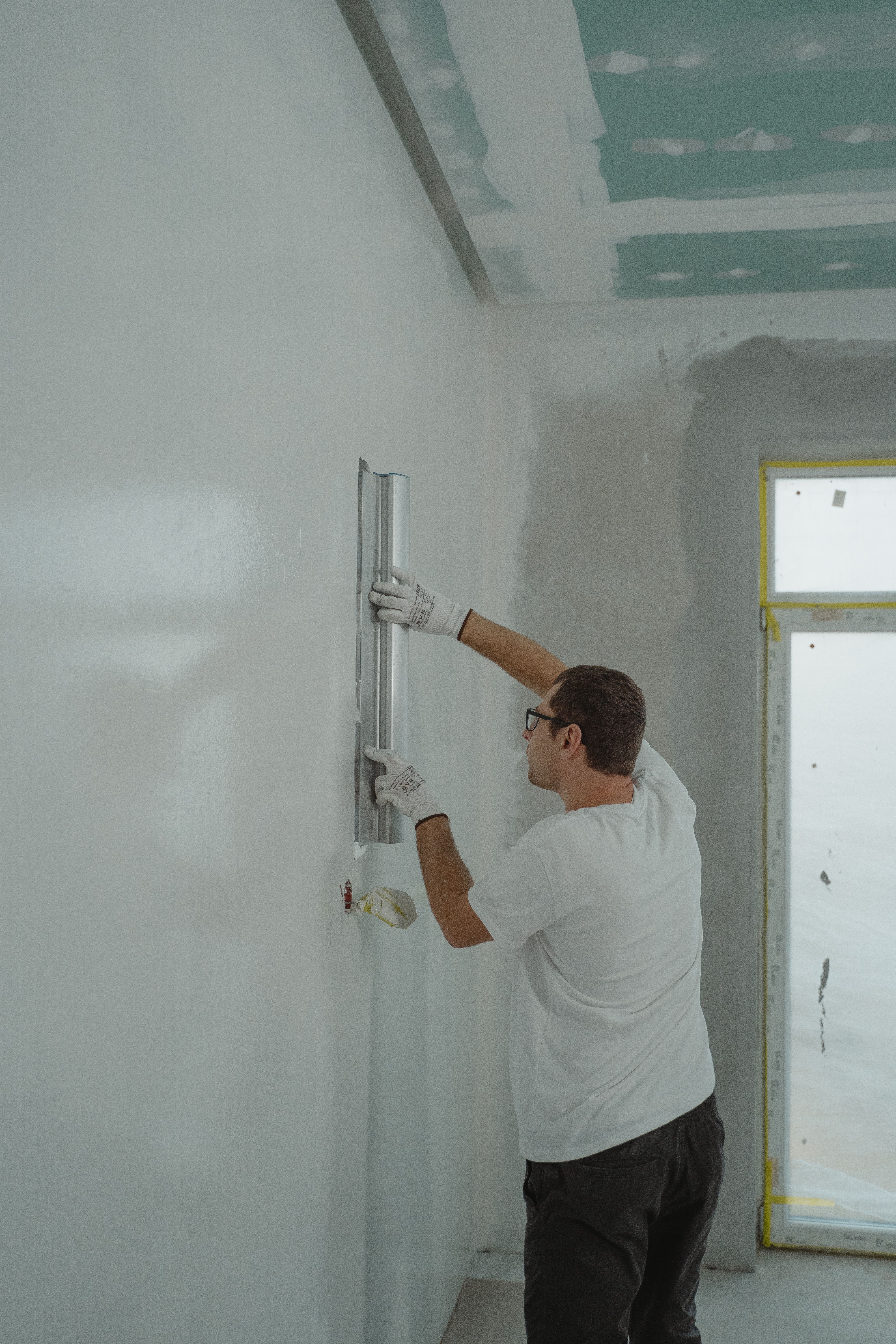 Worker taping and mudding drywall seams